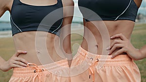 Mid section of fit woman`s torso with her hands on hips. Female runner outdoors slim skinny belly stomatch muscles
