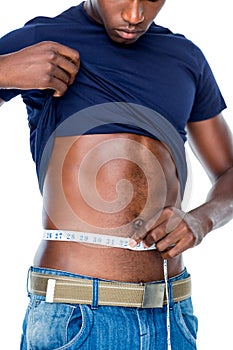 Mid section of a fit young man measuring waist