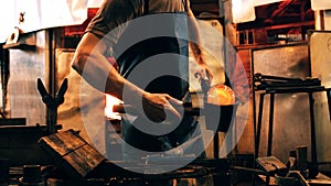 Mid section of glassblower shaping a molten glass