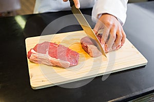 Mid section of hands cutting meat