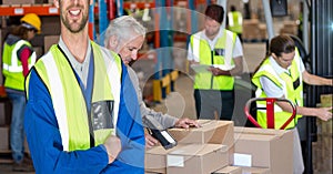 Mid section of happy caucasian worker wearing yellow vest in an warehouse in front of hid colleagues