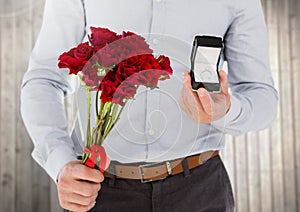 Mid-section of man holding engagement ring and flower bouquet