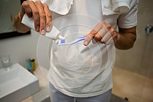 Mid-section of man putting toothpaste on toothbrush