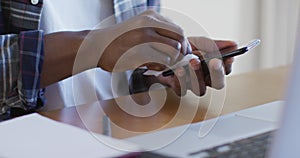 Mid section of man wiping his smartphone with a tissue