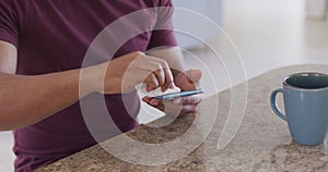 Mid section of man wiping his smartphone with a tissue