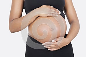 Mid section of pregnant woman touching abdomen over white background