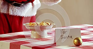 Mid-section of santa claus having milk and breakfast