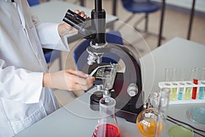 Mid section of schoolgirl experimenting on microscope in laboratory