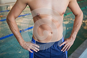 Mid section of a shirtless fit swimmer by pool