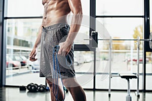 mid section of shirtless sportsman holding skipping rope