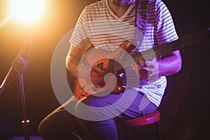 Mid section of singer playing guitar in nightclub