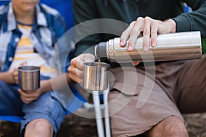 Mid section of son with father pouring drink in cup