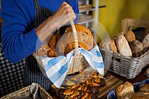 Mid section of staff holding wicker basket of breads at counter