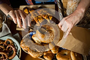 Mid section of staff packing doughnut in paper bag at counter