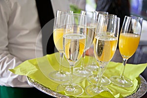 Mid section view of waiter serving champagne and orange juice on