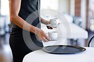 Mid section of waitress serving cup of coffee