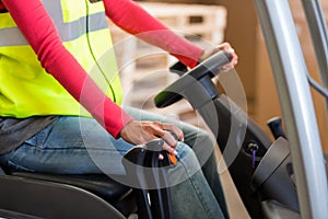 Mid section of warehouse worker using a forklift