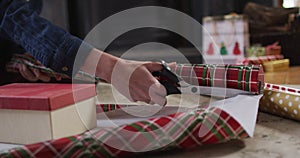 Mid section of woman cutting wrapping paper for Christmas presents at home