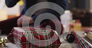 Mid section of woman wrapping Christmas presents at home