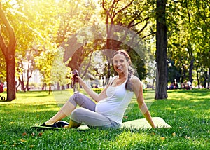 Pregnant woman drinking water in park