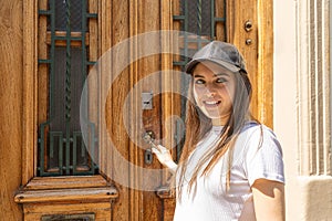 Mid shot of a Young Hispanic woman opening an old wooden door of a house to enter