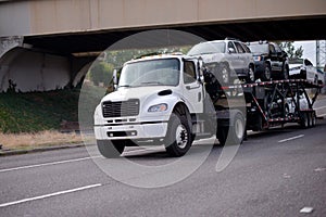 Mid size semi truck car hauler transporting vehicles on the road