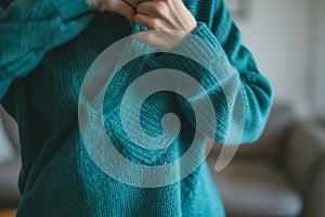 midaction, person pulling on a teal sweater, uncluttered environment