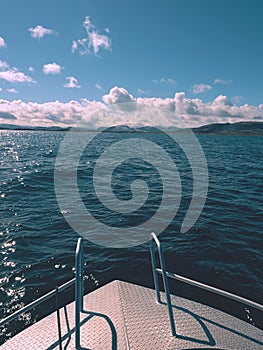 Midday boating in blue sea. Close view from boat bow metal deck. Metal handrail on the deck