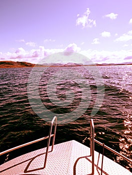 Midday boating in blue sea. Close view from boat bow metal deck. Metal handrail on the deck