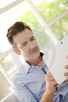 Middel-aged man using a tablet at home