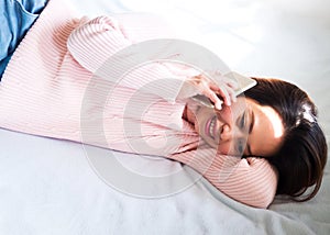 Middle adult Asian woman laying down on bed and using mobile phone. Happiness and lovely emotion. Portrait with copy space.