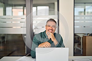 Middle adult business man entrepreneur in office with computer, portrait.