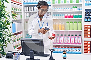 Middle age african american woman pharmacist scanning pills bottle at pharmacy