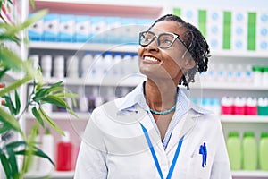 Middle age african american woman pharmacist smiling confident standing at pharmacy