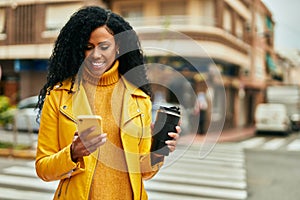 Middle age african american woman using smartphone and drinking coffee at the city