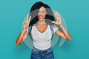 Middle age african american woman wearing casual white t shirt showing and pointing up with fingers number seven while smiling