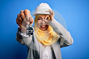 Middle age architect woman wearing muslim hijab and security helmet holding home keys with happy face smiling doing ok sign with