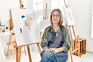 Middle age artist woman at art studio skeptic and nervous, frowning upset because of problem