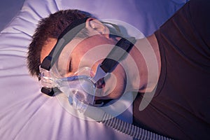 Middle age asian man with sleep apnea sleeping using CPAP machin