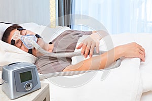 Middle age asian man sleeping wearing CPAP mask connecting to ai