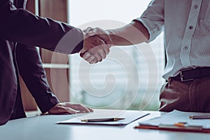 Middle age Asian partner lawyers attorneys shaking hands after discussing a contract agreement done