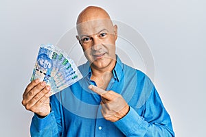 Middle age bald man holding south african 100 rand banknotes smiling happy pointing with hand and finger