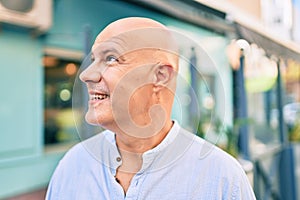 Middle age bald man smiling happy walking at the city
