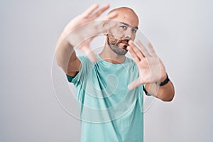 Middle age bald man standing over white background doing frame using hands palms and fingers, camera perspective