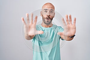 Middle age bald man standing over white background doing stop gesture with hands palms, angry and frustration expression