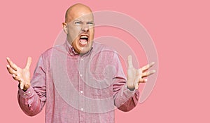 Middle age bald man wearing casual clothes crazy and mad shouting and yelling with aggressive expression and arms raised