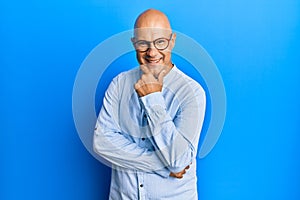 Middle age bald man wearing casual clothes and glasses looking confident at the camera smiling with crossed arms and hand raised