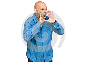 Middle age bald man wearing casual clothes shouting angry out loud with hands over mouth