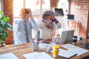 Middle age beautiful business workers working together using laptop at the office suffering from headache desperate and stressed