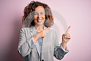 Middle age beautiful businesswoman wearing elegant jacket over isolated pink background smiling and looking at the camera pointing